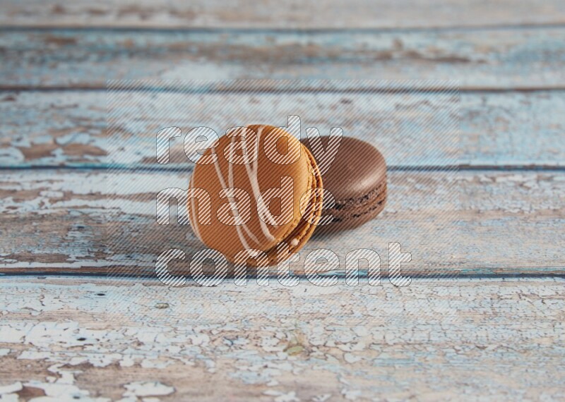 45º Shot of of two assorted Brown Irish Cream, and Brown Dark Chocolate macarons on light blue background