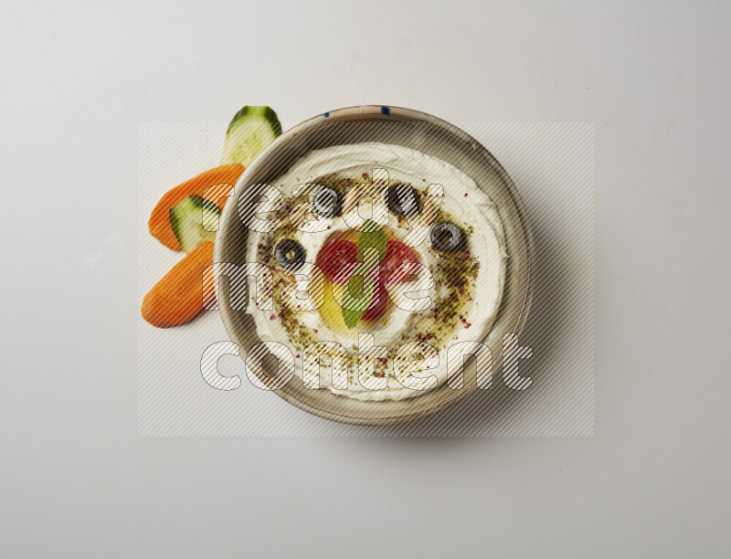 Lebnah garnished with cherry tomato, mint, olives & pine nuts in a grey pottery plate on a white background