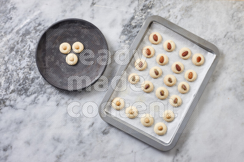 Ghoriba step by step with its ingredient, flour, powdered sugar, ghee and nuts on grey marble background