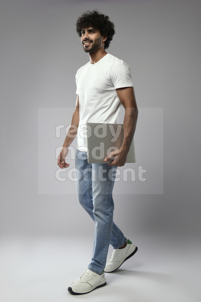 رجل يرتدي ملابس كاجوال يحمل لاب توب علي خلفية بيضاء