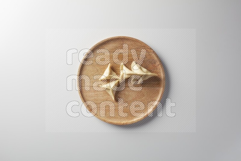 Five Sambosas on a wooden round plate on a white background