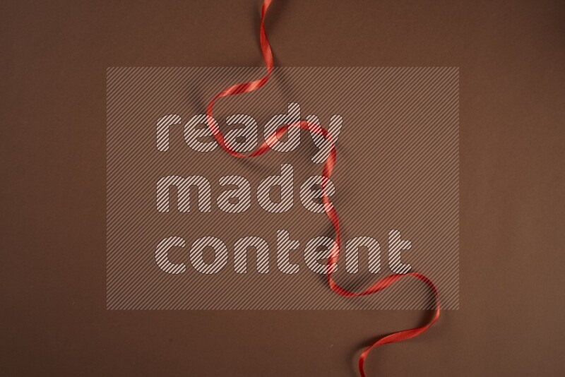 A red collection of sewing and tailoring tools arranged on a brown background