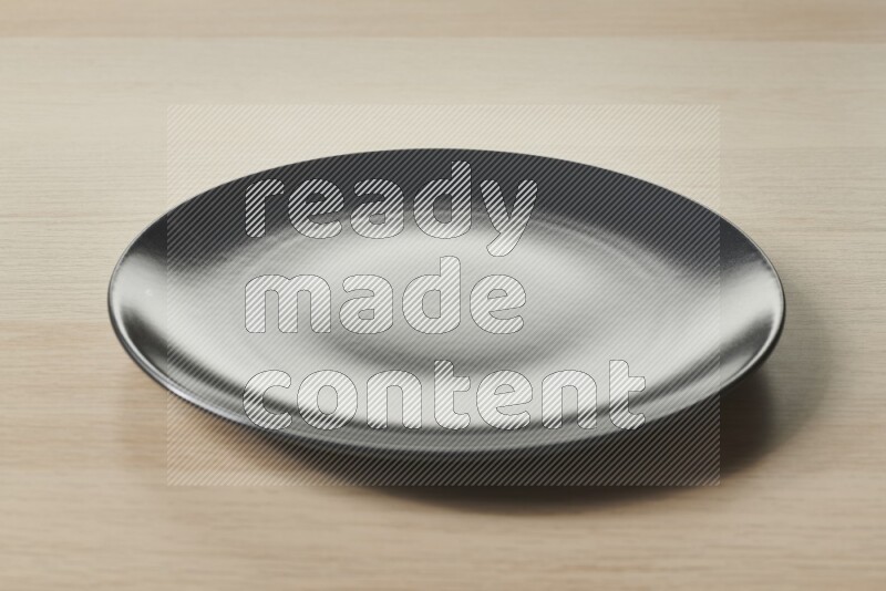 A black ceramic circular plate on light wooden background