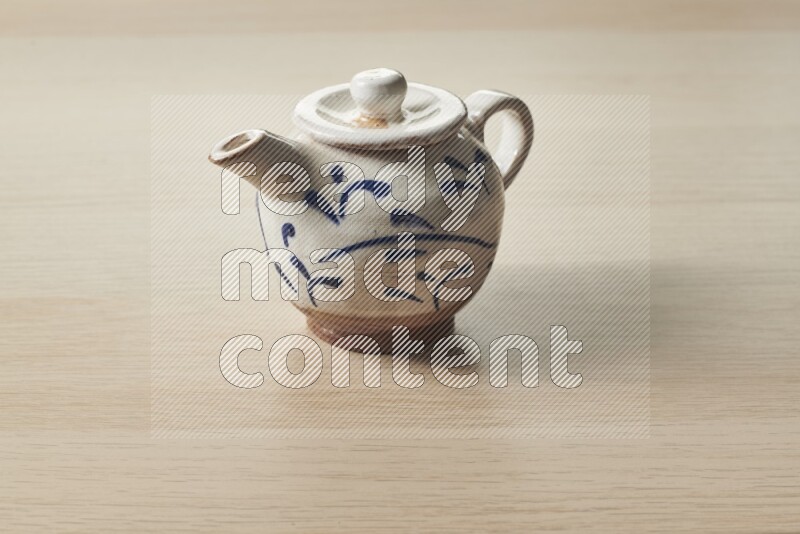 A pottery teapot on light wooden background