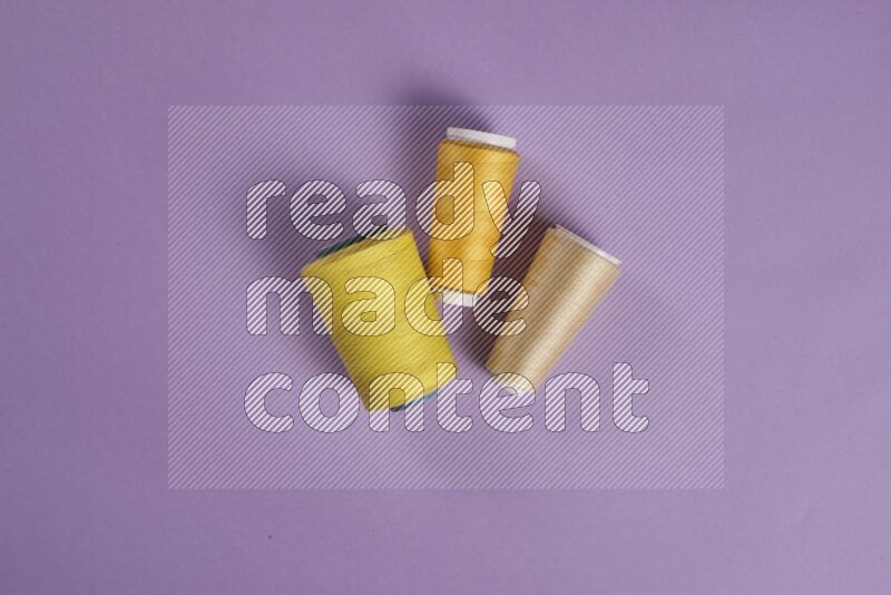 A yellow and purple collection of sewing and tailoring tools arranged on a purple background
