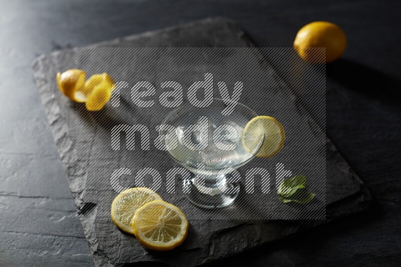 A glass of lemon juice with a lemon slice on black background