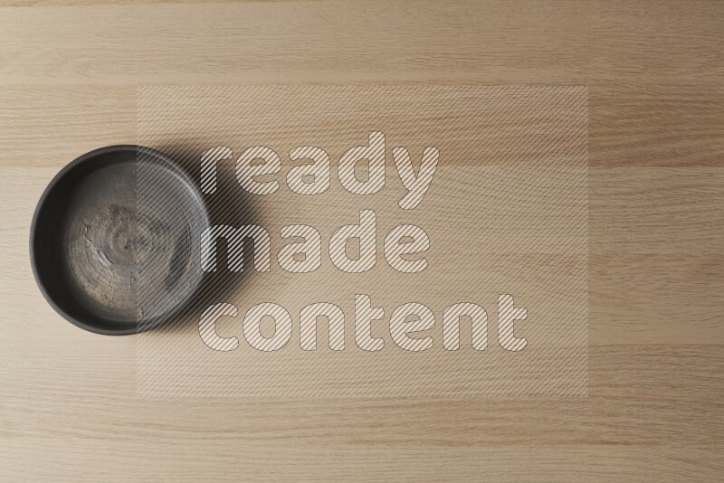 A black pottery oven bowl on light wooden background