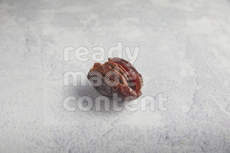 pecan stuffed madjoul date on a light grey background