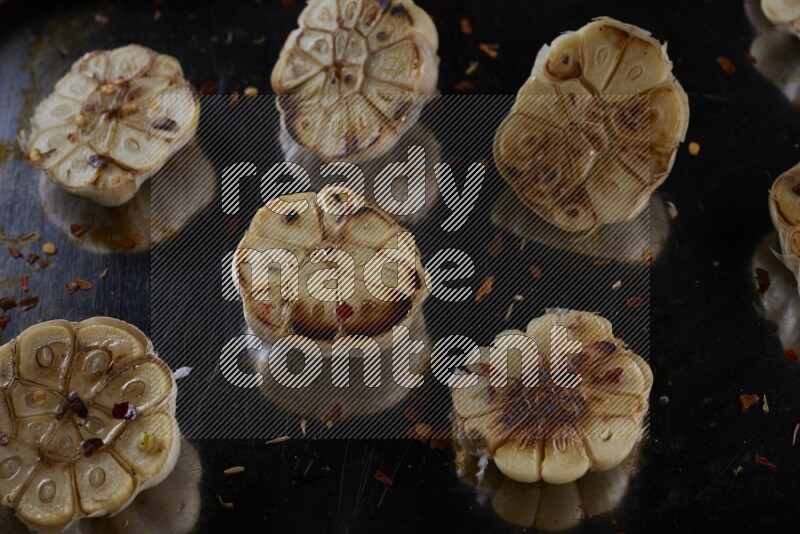 half's roasted garlic in a stainless tray on a grey textured countertop
