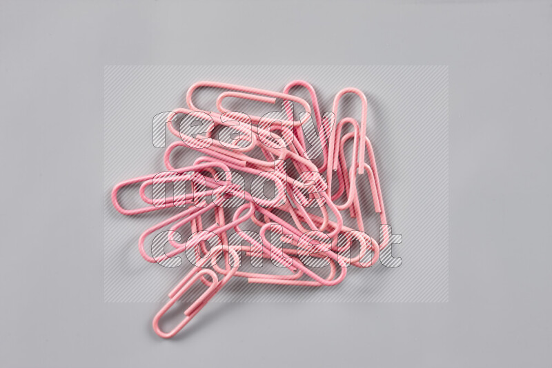 Pink paper clips isolated on a grey background
