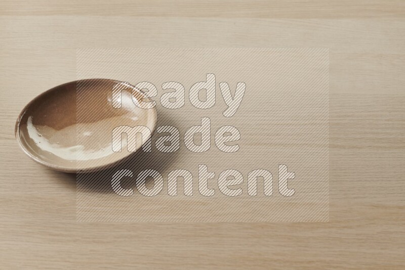 A multicolored pottery plate on light wooden background
