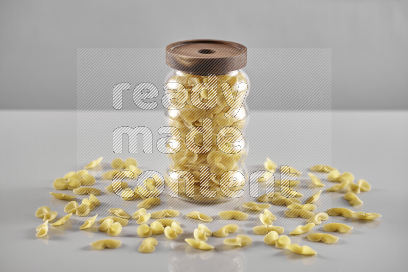Raw pasta in a glass jar on light grey background