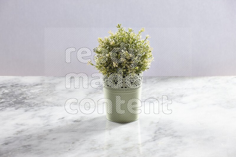 Artificial plant in green decorative pot on grey marble background