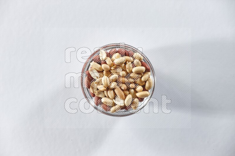 A glass bowl full of peeled peanuts on a white background in different angles