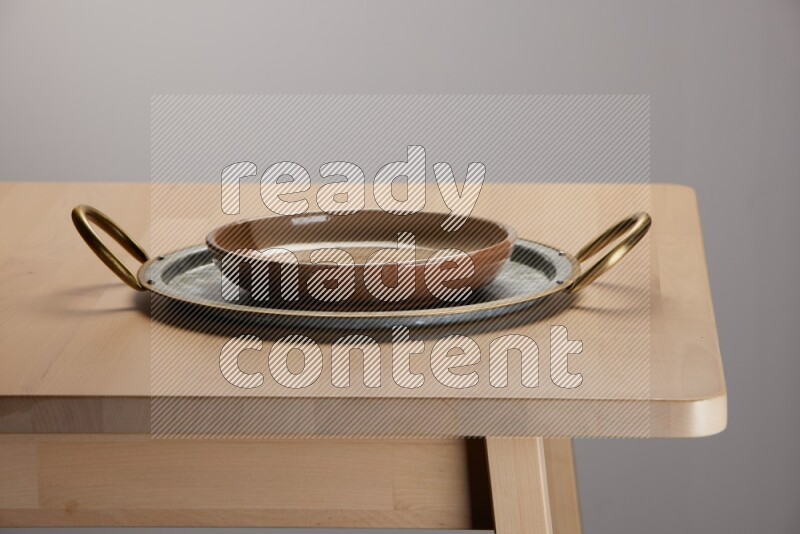 multicolored plate placed on a rounded stainless steel tray with golden handels on the edge of wooden table