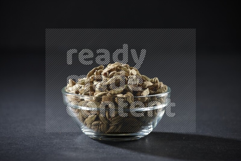 وعاء زجاجي ممتلئ بحبوب الهيل علي خلفية سوداء