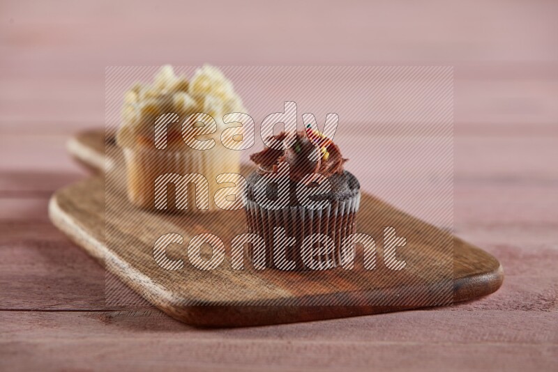 Chocolate mini cupcake topped with chocolate cream on a wooden board