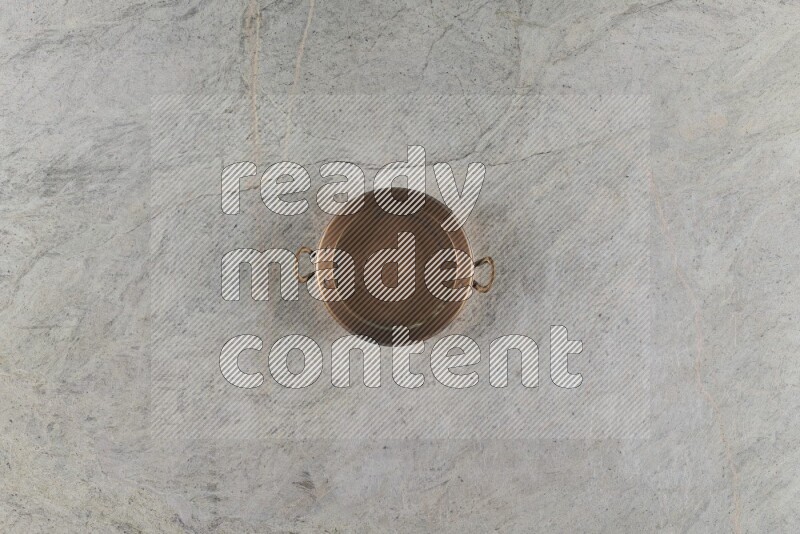 A small copper pan on grey marble background