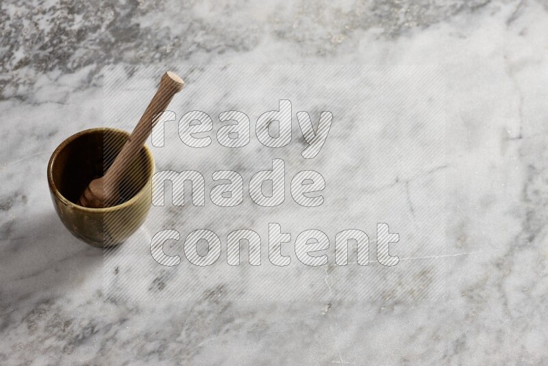 Multicolored pottery cup with wooden honey dipper in it on grey marble background