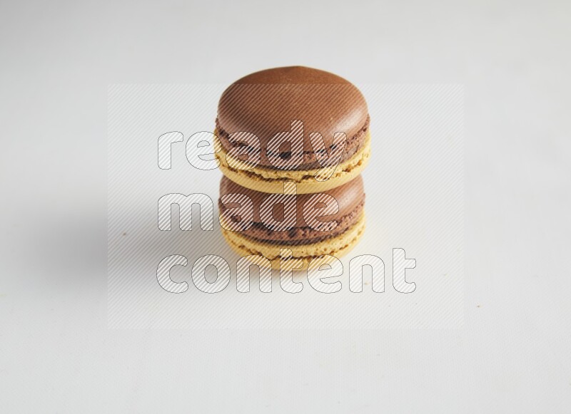 45º Shot of two Yellow and Brown Chai Latte macarons on white background