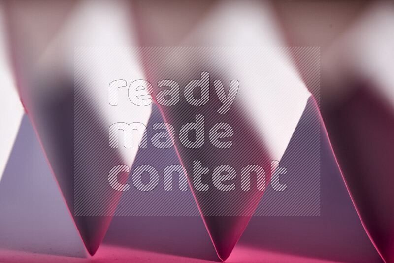A close-up abstract image showing sharp geometric paper folds in white and pink gradients