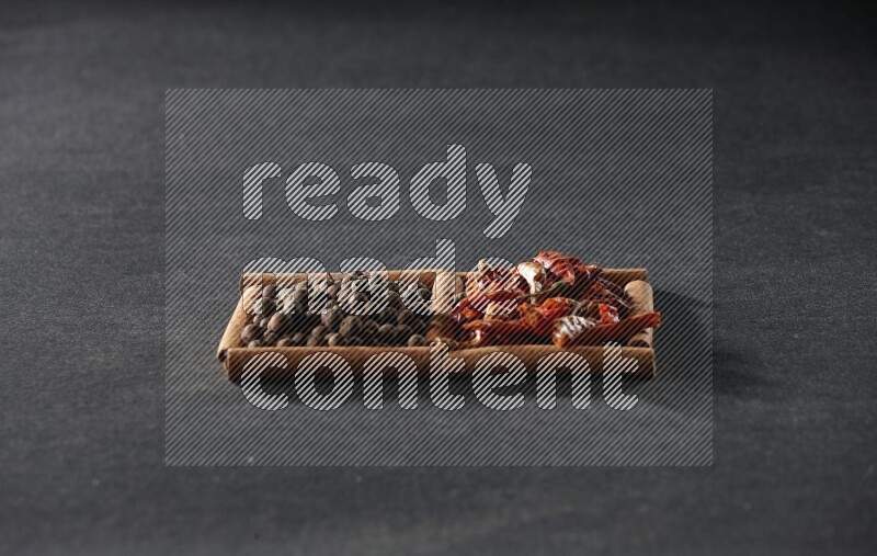 2 squares of cinnamon sticks full of chilis and allspice on black flooring