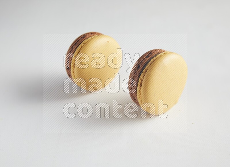 45º Shot of two Yellow and Brown Chai Latte macarons on white background