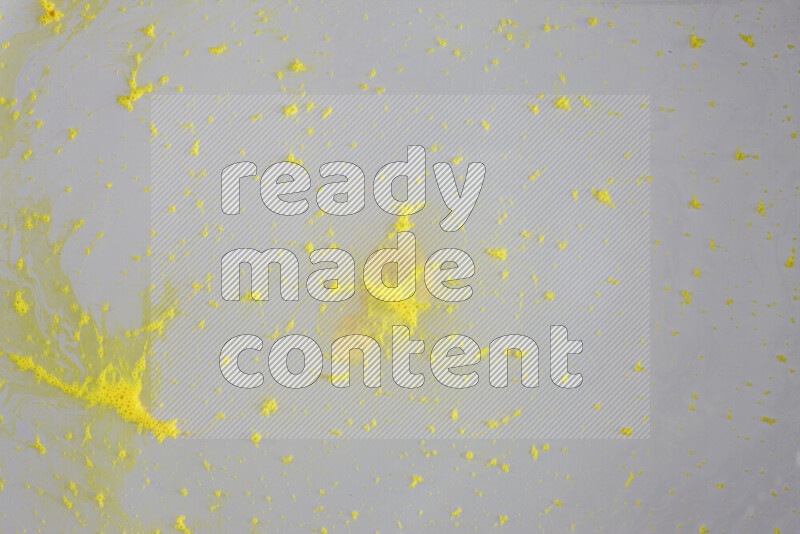 The image captures a dramatic splatter of yellow paint over a white backdrop