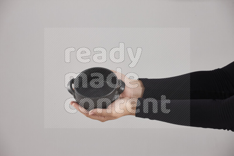 امرأة ترتدي عباءة سوداء تحمل أدوات فخارية مختلفة في أوضاع متعددة