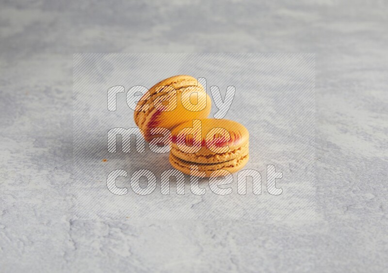 45º Shot of two orange Exotic macarons on white  marble background