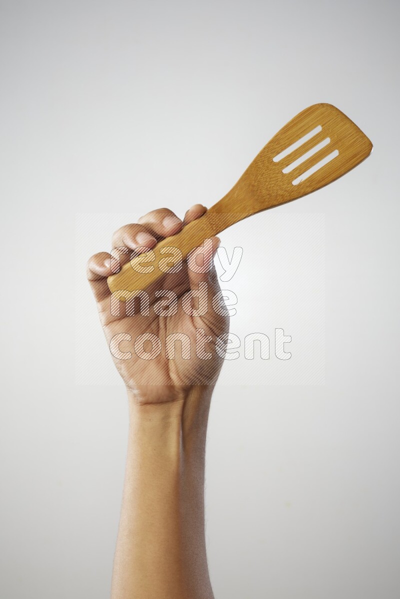 Male Hand Holding Slotted Turner on white background