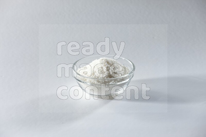 A glass bowl full of desiccated coconut on a white background in different angles