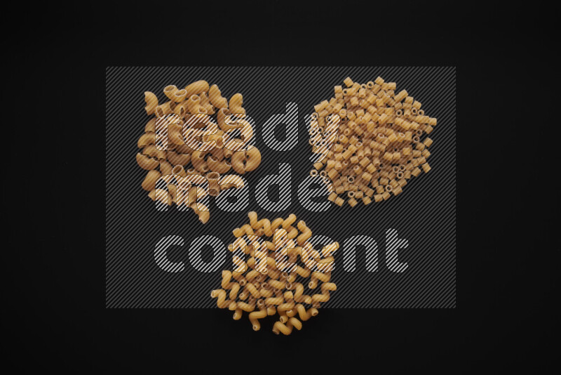 Different pasta types in bunches on black background
