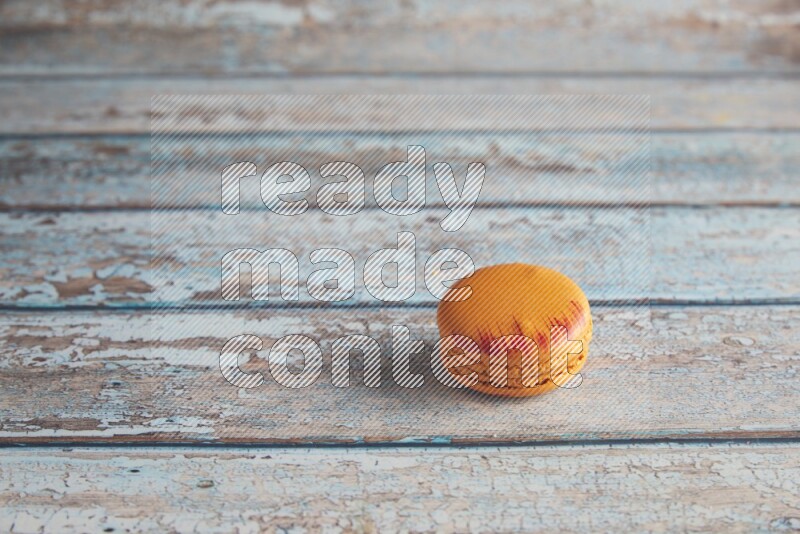 45º Shot of Orange Exotic macaron on light blue wooden background