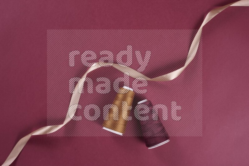 A brown and red collection of sewing and tailoring tools arranged on a red background