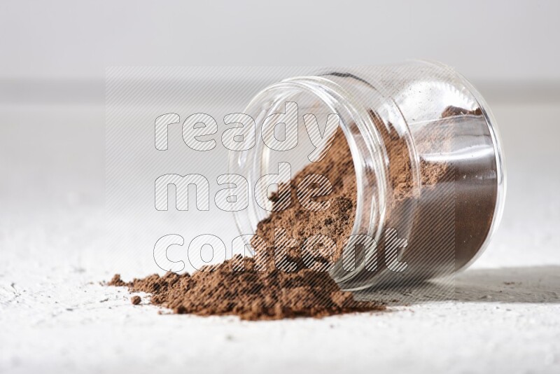 A flipped glass jar full of cloves powder on a textured white flooring