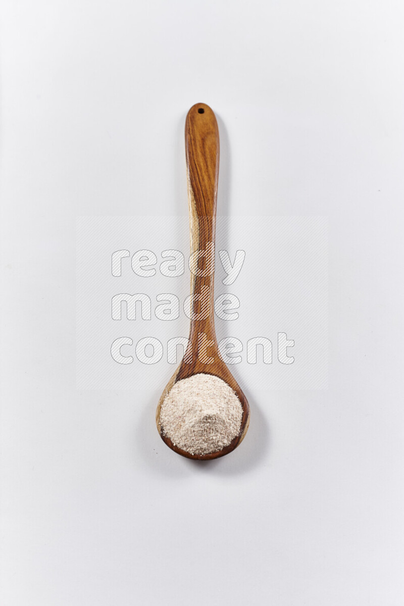 A wooden ladle full of onion powder on white background