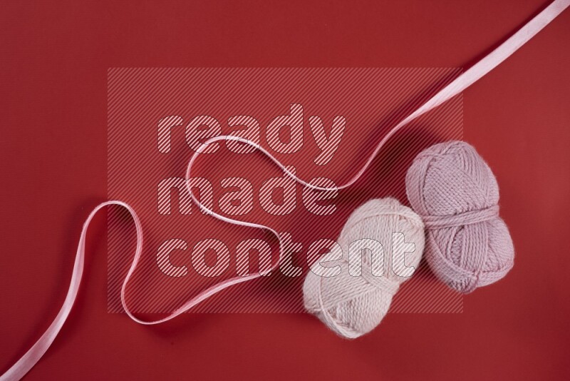 A pink and red collection of sewing and tailoring tools arranged on a red background