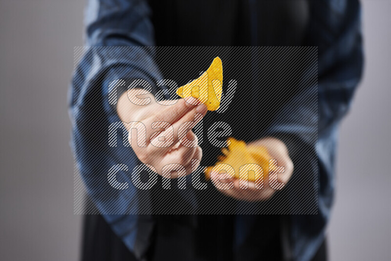 Woman in abaya holding different kinds of snacks in different positions