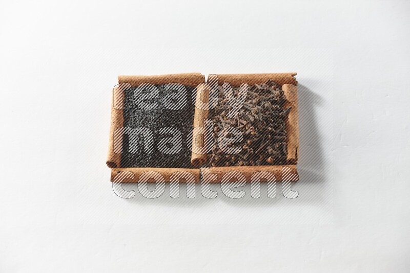 2 squares of cinnamon sticks full of cloves and black seeds on white flooring