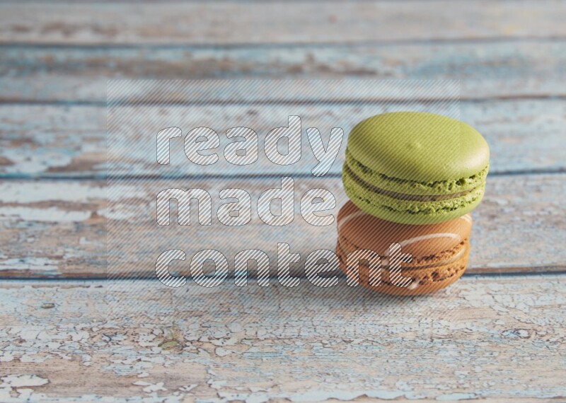 45º Shot of of two assorted Brown Irish Cream, and Green Pistachio macarons  on light blue background