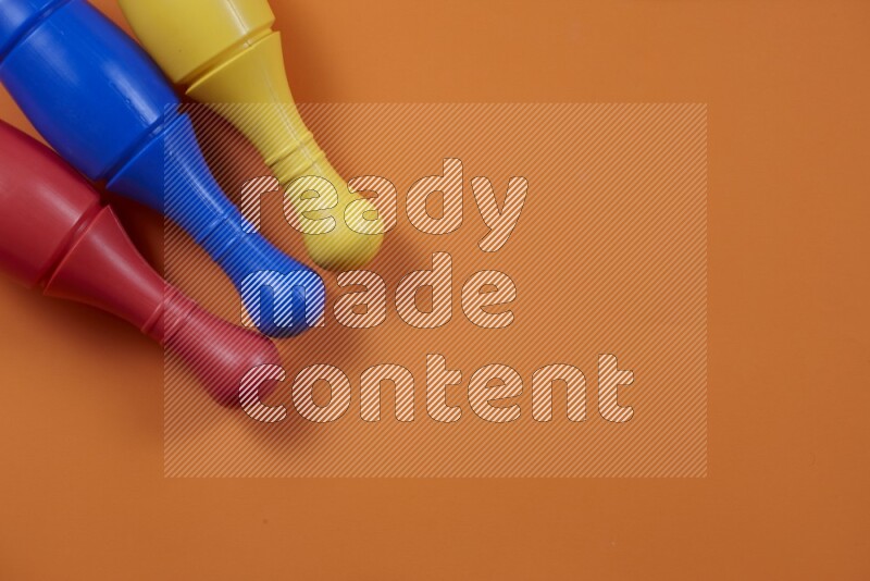 أوتاد البولينج البلاستيكية الملونة علي خلفيات ملونة مختلفة (ألعاب أطفال)