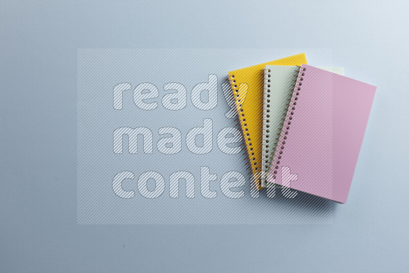 Multicolored notebooks with different school supplies on blue background