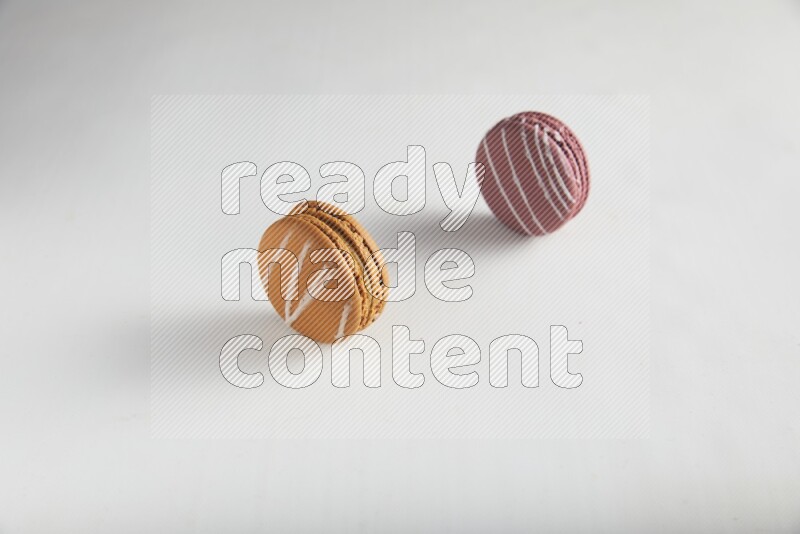 45º Shot of of two assorted Brown Irish Cream, and Red Poppy Flower macarons on white background