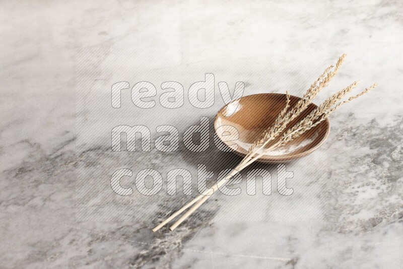 Wheat stalks on multicolored pottery plate on grey marble background