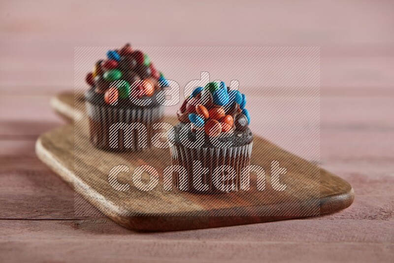 Chocolate mini cupcake topped with m&ms on a wooden board