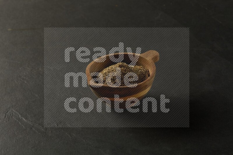wooden round sauce bowl filled with herbs on grey textured countertop