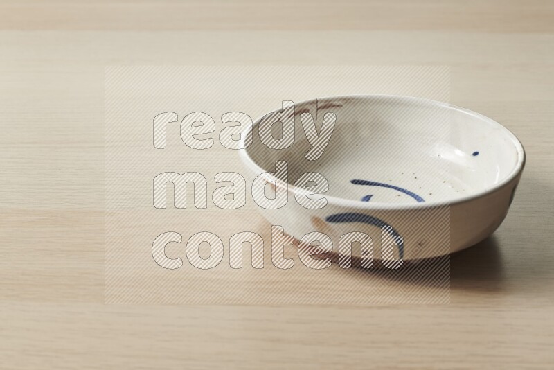 A multicolored pottery bowl on light wooden background