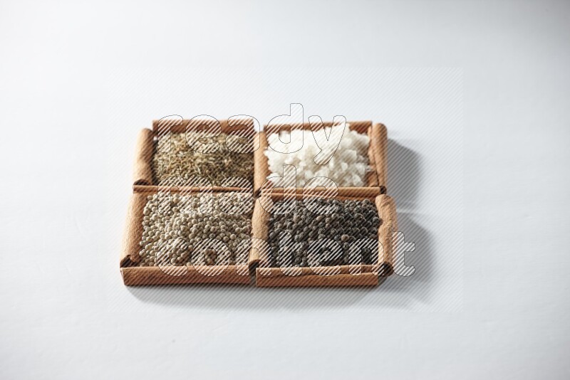 4 squares of cinnamon sticks full of cumin, salt, white pepper and black pepper on white flooring