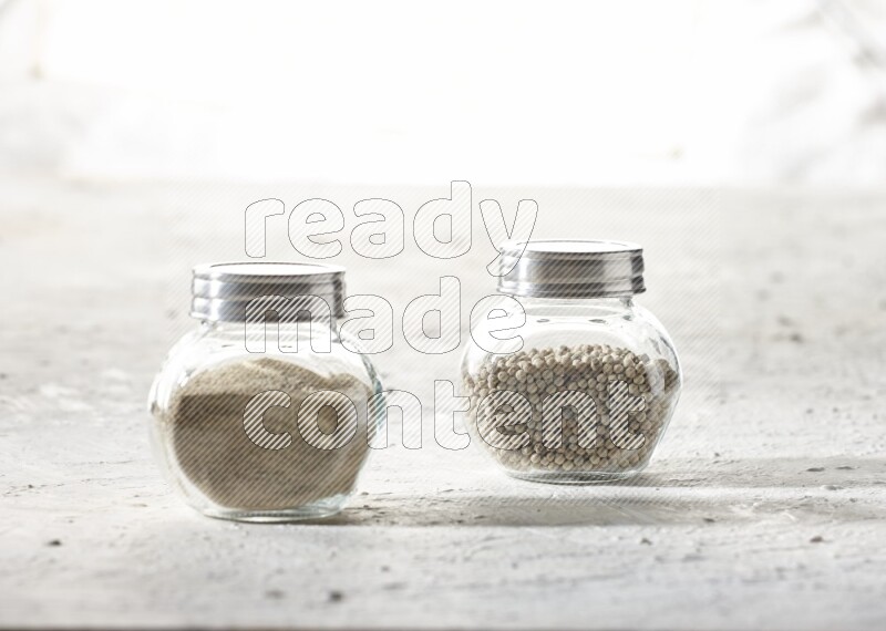 2 Herbal Glass jar full of white pepper beads and powder on textured white flooring